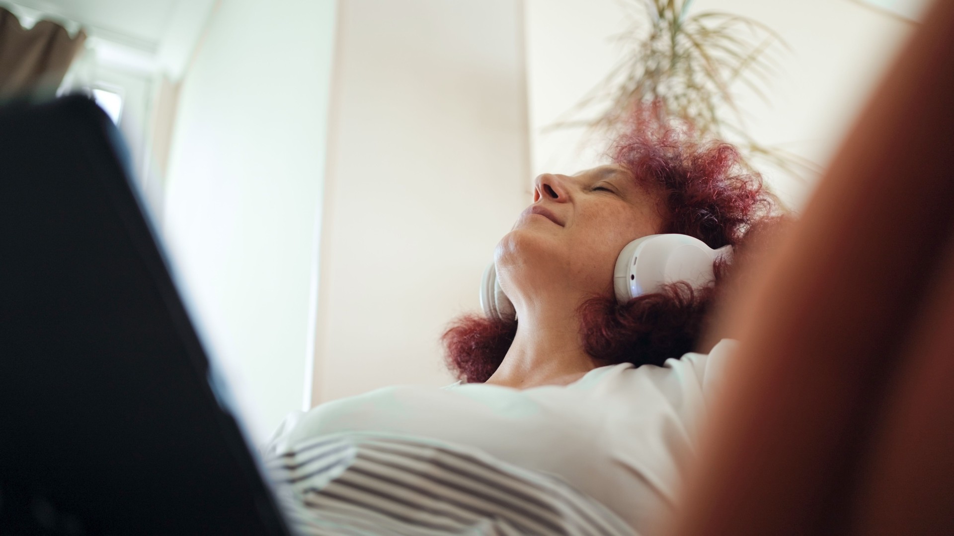 Mature woman relaxing with music at home.