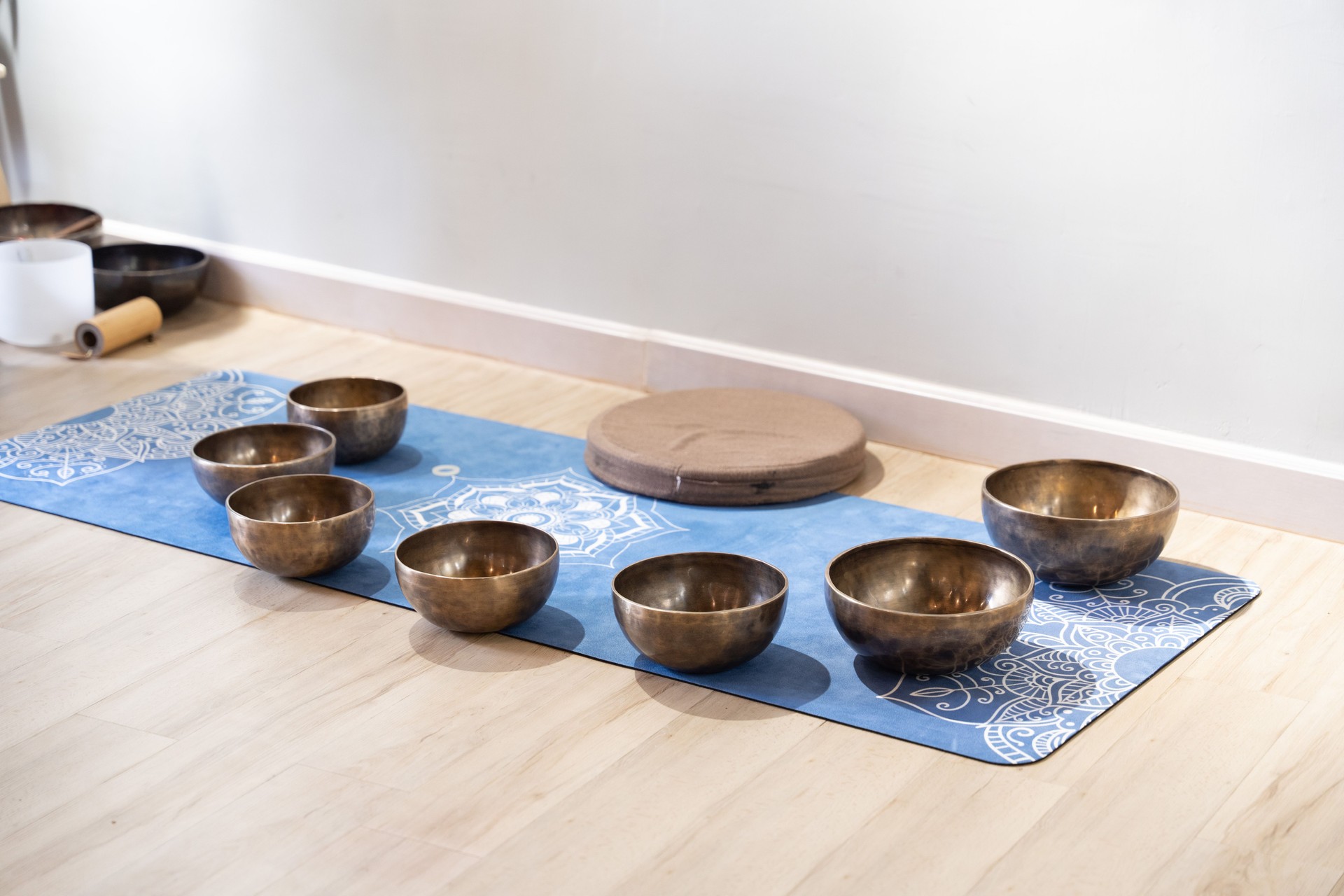 A photograph displaying a singing bowl, commonly used for healing purposes, positioned on a wooden floor